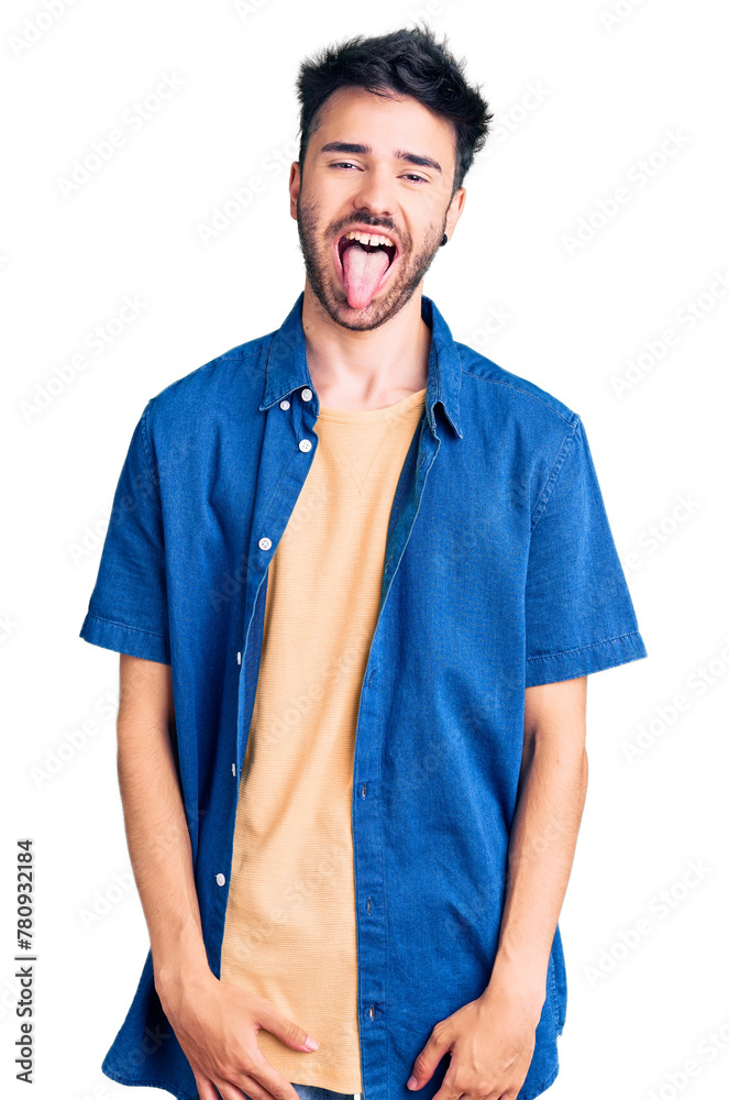 Young hispanic man wearing casual clothes sticking tongue out happy with funny expression. emotion concept. Young hispanic man wearing casual clothes sticking tongue out happy with funny expression. emotion concept.