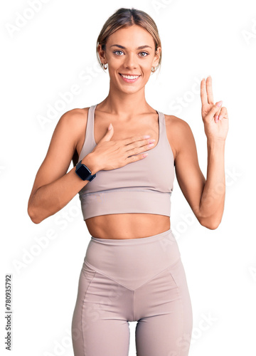 Beautiful caucasian woman wearing sportswear smiling swearing with hand on chest and fingers up, making a loyalty promise oath