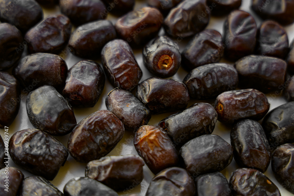 Heap of dried dates on white food background from top view. An abstract pattern of irregularly stacked brown dates Heap of dried dates on white food background from top view. An abstract pattern of irregularly stacked brown dates