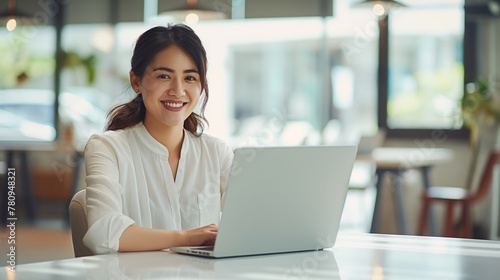 Business woman working on a laptop in a bright, open workspace. A young student or remote teacher is working in online education, remote work. Free Download Business woman working on a laptop in a bright, open workspace. A young student or remote teacher is working in online education, remote work. - GFXLoad