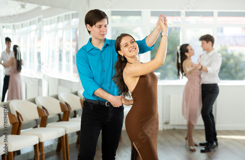Couple in festive clothes learn to dance latin american dance bachata in studio