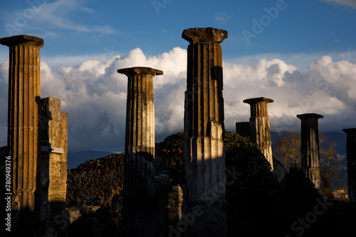 An ancient, weathered columns standing tall against a dramatic sky filled with fluffy clouds,