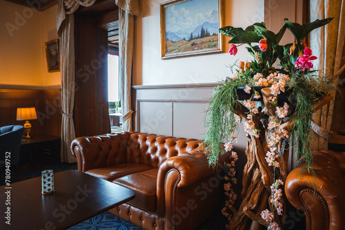 Photos Cozy lounge space with classic decor featuring a Chesterfield sofa in rich brown leather, a wooden coffee table, floral arrangement, and landscape painting