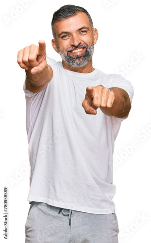 Middle age handsome man wearing casual white tshirt pointing to you and the camera with fingers, smiling positive and cheerful