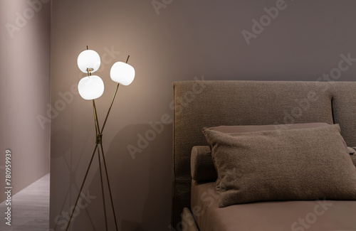 Interior furnishing detail of a modern bedroom with bed and fabric blankets and warm light lighting