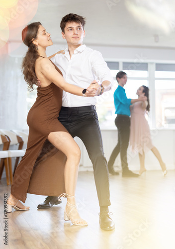 While doing rehearsal of reporting concert, guy and girl participants of dance workshop perform quickstep. Two couples practice their skills in performing quickstep during attending dancing school.