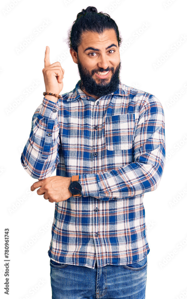 Young arab man wearing casual clothes with a big smile on face, pointing with hand and finger to the side looking at the camera. Young arab man wearing casual clothes with a big smile on face, pointing with hand and finger to the side looking at the camera.