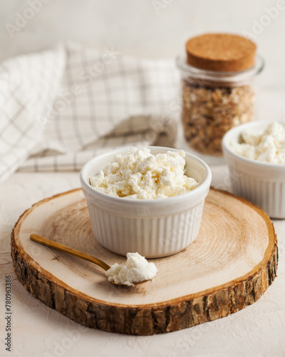 Fresh homemade crumbly cottage cheese in a bowl, farm-fresh produce.
