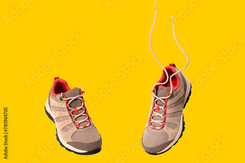 pair of comfortable New brown trekking sneakers, waterproof hiking boots with laces isolated on yellow background, modern footwear, natural suede for outdoor hiking, camping