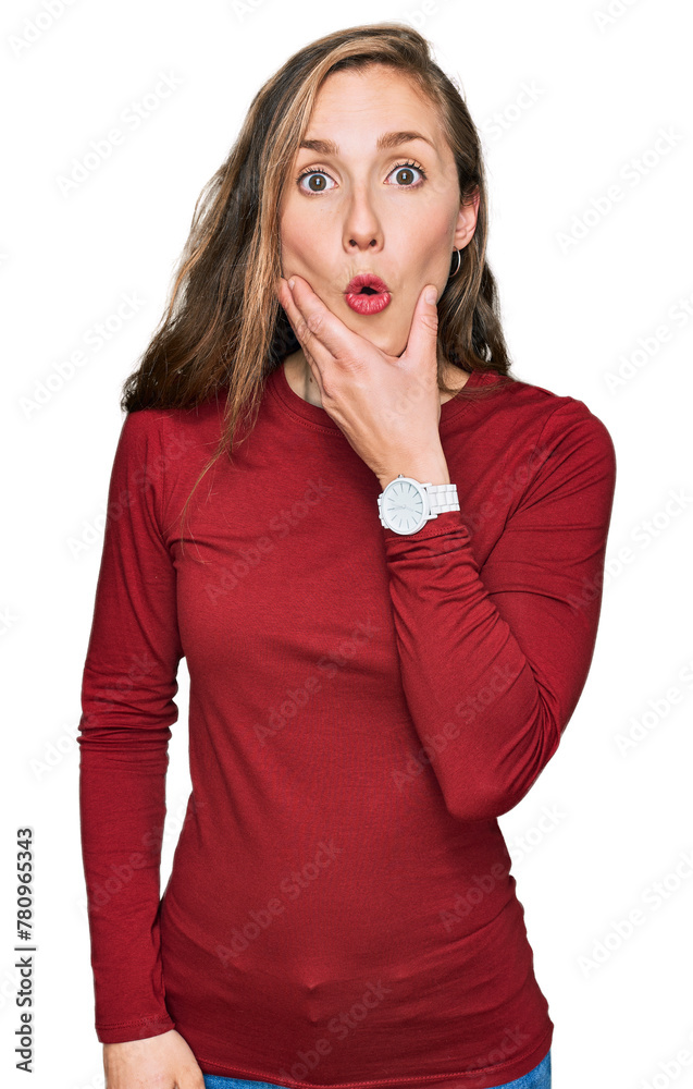 Young blonde woman wearing casual clothes looking fascinated with disbelief, surprise and amazed expression with hands on chin Young blonde woman wearing casual clothes looking fascinated with disbelief, surprise and amazed expression with hands on chin