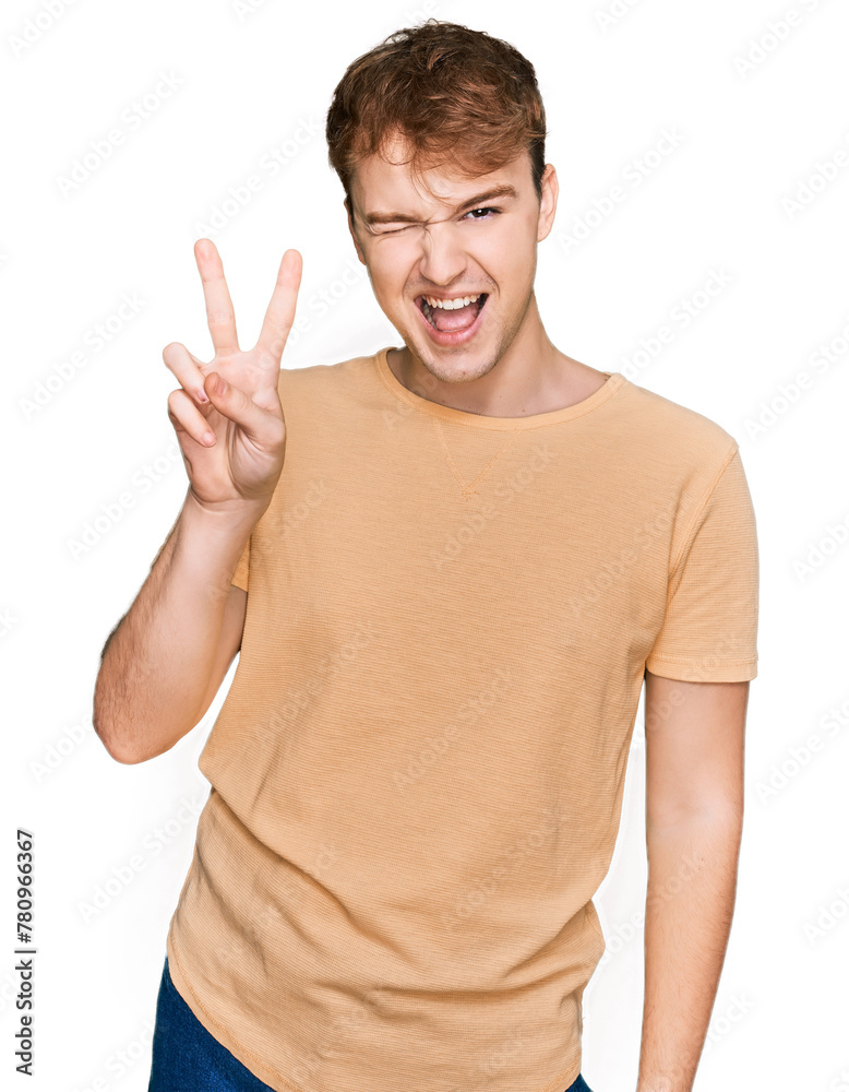 Young caucasian man wearing casual clothes smiling with happy face winking at the camera doing victory sign with fingers. number two. Young caucasian man wearing casual clothes smiling with happy face winking at the camera doing victory sign with fingers. number two.