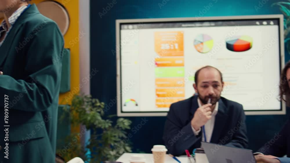 Corporate workers looking into project updates and timelines in boardroom, establishing budget and activities to achieve strategic objectives in a competitive business environment. Camera B.