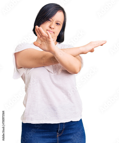 Brunette woman with down syndrome wearing casual white tshirt rejection expression crossing arms and palms doing negative sign, angry face