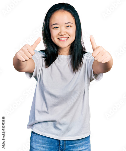 Young chinese woman wearing casual white t shirt approving doing positive gesture with hand, thumbs up smiling and happy for success. winner gesture.