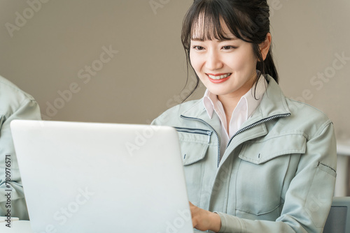Plakat パソコンで仕事する作業服・作業着姿の若いアジア人ビジネスウーマン（建築士・設計士） 