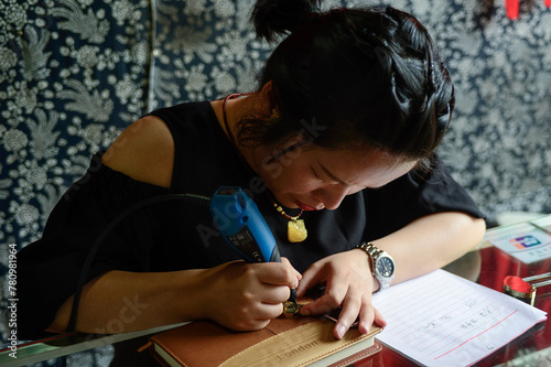 Canvastavla A local engraver etches an inscription on a love lock to be hung alongside red blessing ribbons in Zhangjiajie National Forest Park, China