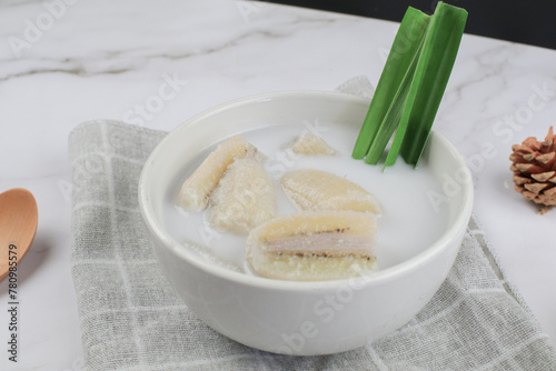 Banana in coconut milk or Kluay Buad Chee with pandan leaf in white bowl. Popular food Thai traditional sweets or snack. photo