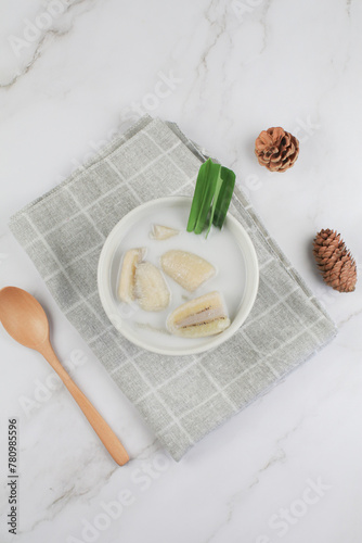 Banana in coconut milk or Kluay Buad Chee with pandan leaf in white bowl. Popular food Thai traditional sweets or snack. photo
