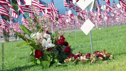 A close-up of a memorial bouquet surrounded by American flags on a vibrant green lawn, paying respects to the 9.11 victims. Slow motion. Footage 4K.  photo