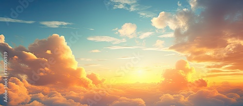 Fluffy clouds fill the sky as the bright orange sun sets in the background, creating a stunning sunset scene