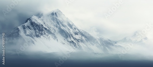 Majestic snowy mountain peak shrouded in clouds, creating a serene and picturesque scene in nature
