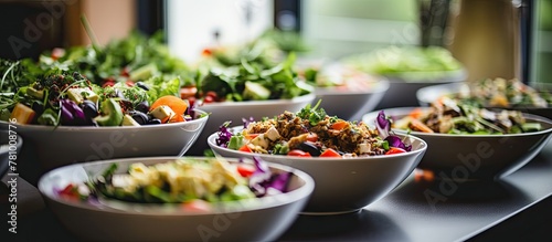 Multiple bowls of fresh salads neatly arranged on a table in front of a window, creating a vibrant display
