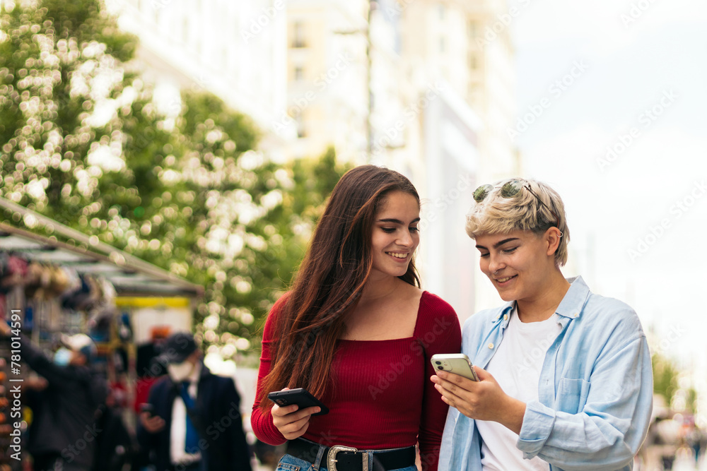 two teenager girls walking and watching mobile