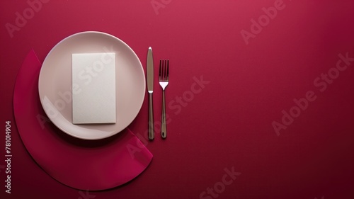 Elegant table setting with white square plate, cutlery, and pink napkin on maroon background photo