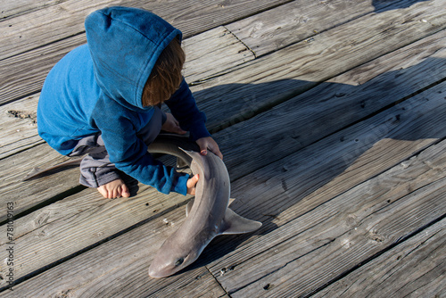 boy holding mud shark on ocean pier © Bill Keefrey