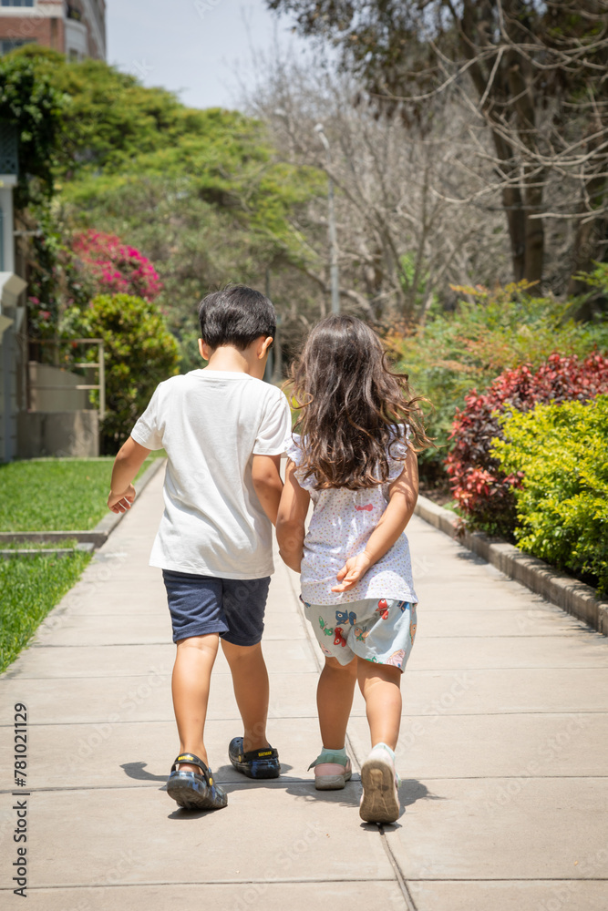 Two little siblings walking in a park Two little siblings walking in a park