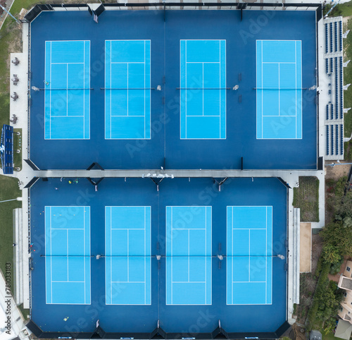 Aerial view of eight tennis courts covered with blue artificial turf