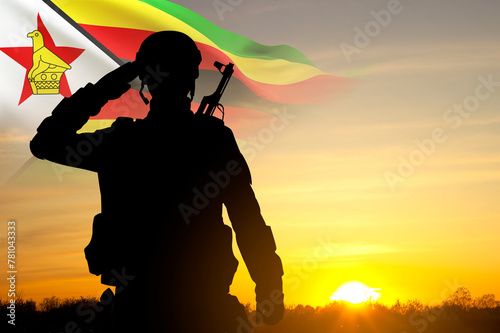 Silhouette of a saluting soldier with Zimbabwe flag against the sunset photo