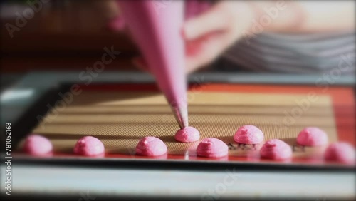 Woman pastry chef making pastel pink macaroons dessert. Process of piping macaron dough 