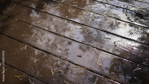 Close-up of a wet porch on a wooden terrace, drops of water falling creating circles. Summer rain. photo