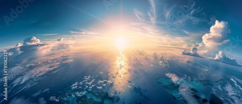 A breathtaking view of the Earth from space, with the sun casting its warm glow over an expansive ocean and land mass. The blue sky is dotted with clouds, creating a serene atmosphere that captures na