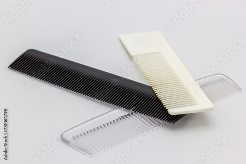 Three different colored combs on a white background. All three of the combs are plastic.  (ID: 781064798)