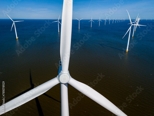 A cluster of towering wind turbines stands tall in the ocean, their blades gracefully spinning in the spring breeze, harnessing the power of the wind to produce clean energy.