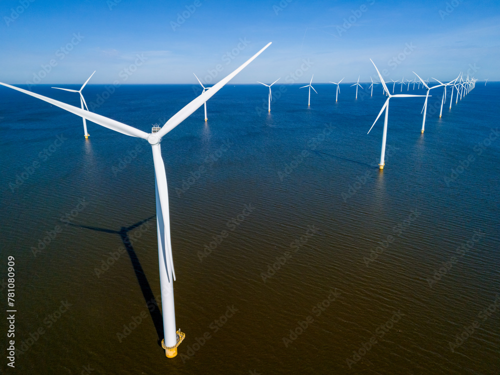 A group of wind turbines majestically spin in the ocean, harnessing the ...