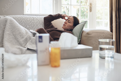 Tired woman, sick and headache with medication on sofa for flu, cold or sinus in living room at home. Young female person with illness, fever or influenza in fatigue or rest on couch from paracetamol