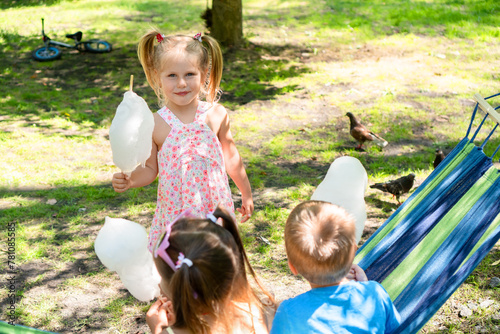 Cheerful group of five-year-old kids relishing sweet cotton candy while spending a delightful summer day in the park, creating beautiful memories and spreading happiness.