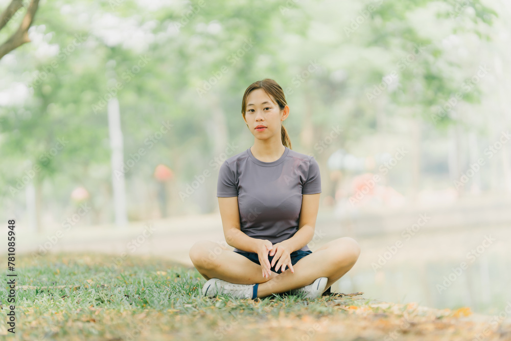 Asian woman stretching and warming up before going for a run at the park. Yoga, health care, weight loss exercise.