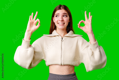 A woman dressed in a skirt and sweater is standing and waving her hand in the air, possibly in a greeting or to get someones attention.