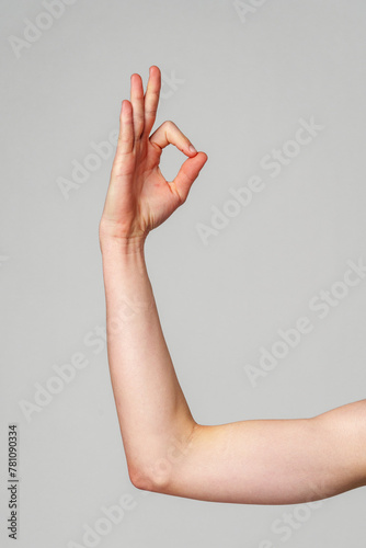 Close-Up of a Hand Gesturing OK Sign Against a Neutral Background