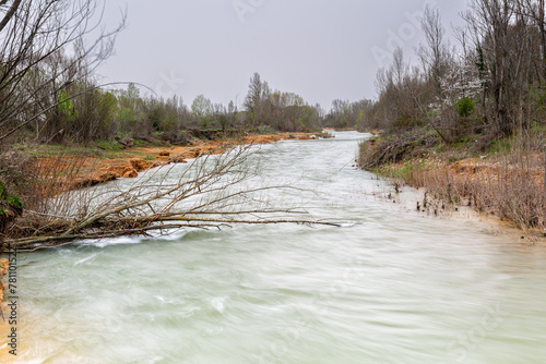 Flood of the Bernesga River after the mountain thaw in early spring and fallen tree, León, Spain. photo