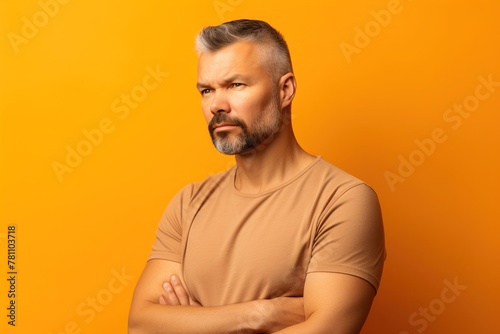 A man with a beard and gray hair is standing in front of a yellow wall