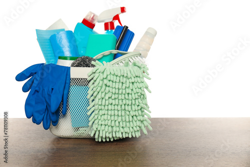 Different cleaning products in basket on wooden table against white background