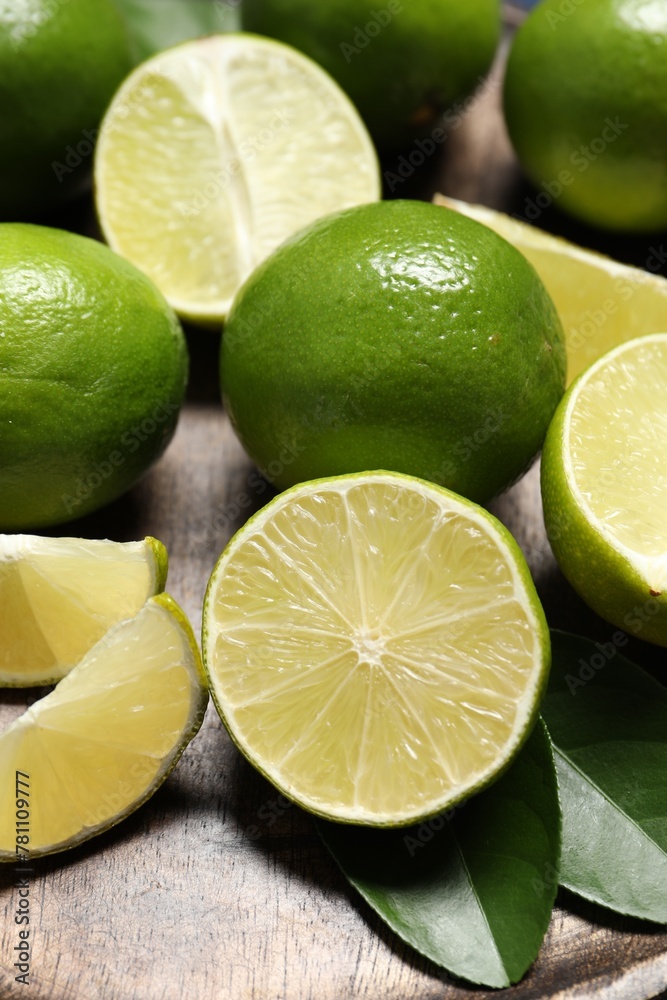 Fresh ripe limes and leaves on table, closeup Fresh ripe limes and leaves on table, closeup