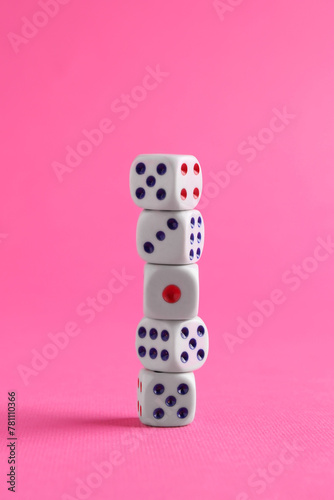 Many stacked game dices on pink background