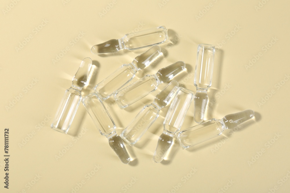 Glass ampoules with liquid on beige background, top view Glass ampoules with liquid on beige background, top view
