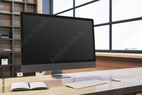 Close up of modern designer office workplace with empty computer monitor, window with city view and wooden shelves in the background. Mock up, 3D Rendering.